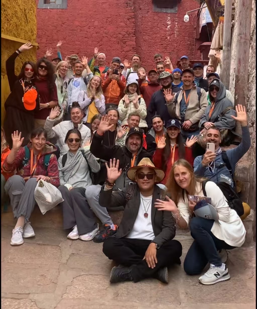 Large group sitting on monastery steps waving